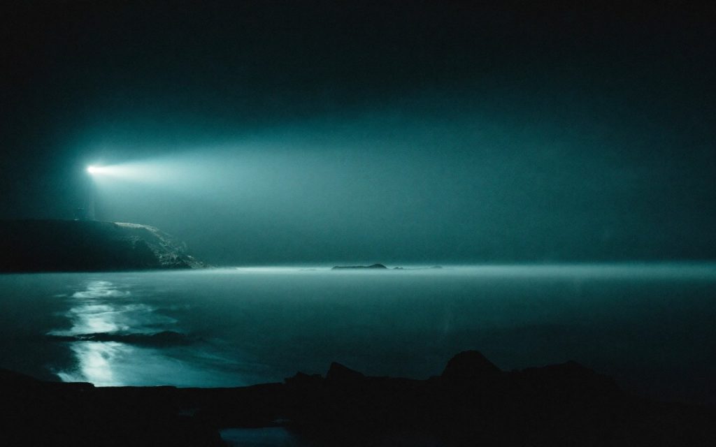 Faro iluminando la niebla sobre el mar