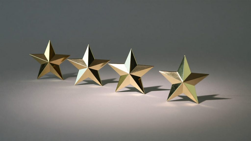 Cinco estrellas doradas en fila sobre una superficie clara
