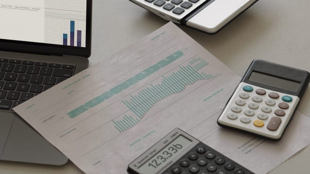 Escritorio con calculadora, presupuestos impresos y portátil con una maqueta web